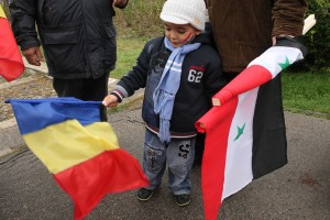 Un copil se joaca cu două steaguri in timpul mitingului de protest al comunitatii siriene din Bucuresti. Foto: Oana Pavelescu