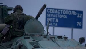 A soldier atop a Russian armored personnel carriers with a road sign reading "Sevastopol - 32 kilometers, Yalta - 70 kilometers", near the town of Bakhchisarai, Ukraine, Feb. 28, 2014. (AP)